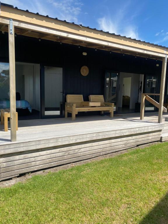 a wooden deck with a bench on a house at Whangamata Bach Life in Whangamata