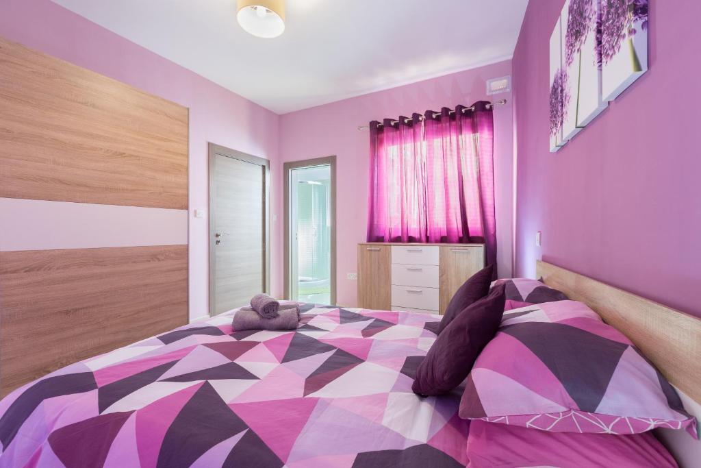 een paarse slaapkamer met een groot bed met een teddybeer erop bij North Side Apartment 1 in Mġarr