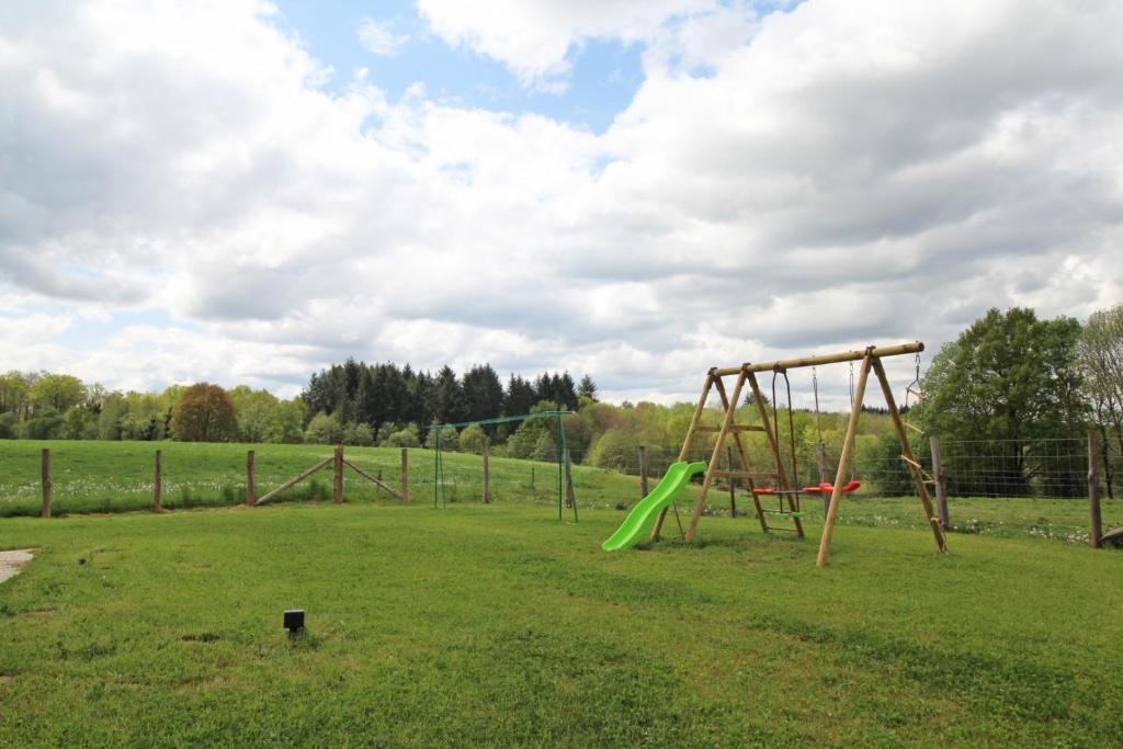 a playground with a green swing set in a field at La reille in Cussac