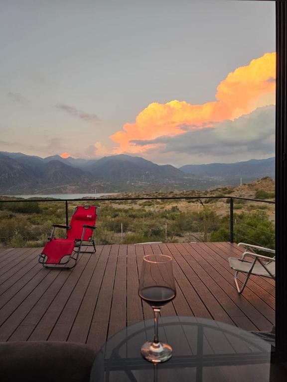 two red chairs and a glass table on a wooden deck at Altos Dique Potrerillos in Potrerillos