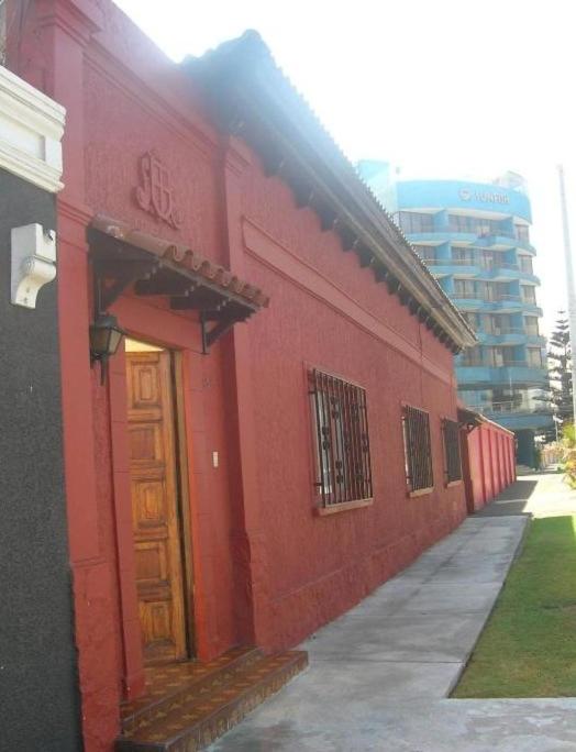 a red building with a door on a street at Iquique Beachfront -frente a playa Cavancha- in Iquique