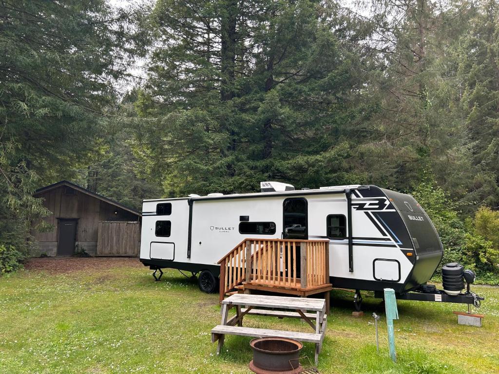 a white rv parked in a yard with a porch at The Bunkhouse Camper in Klamath