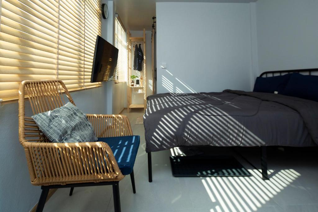 a bedroom with a bed and two wicker chairs at Uncle NID Hostel in Lat Krabang