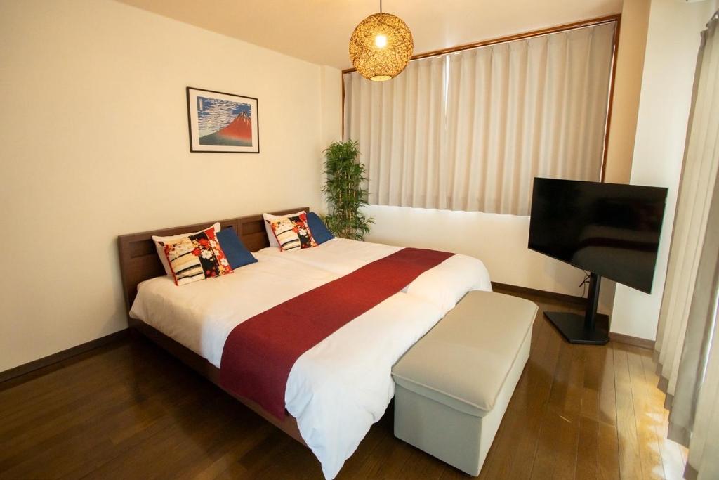a bedroom with a bed and a flat screen tv at Nagano Station Inn East in Nagano