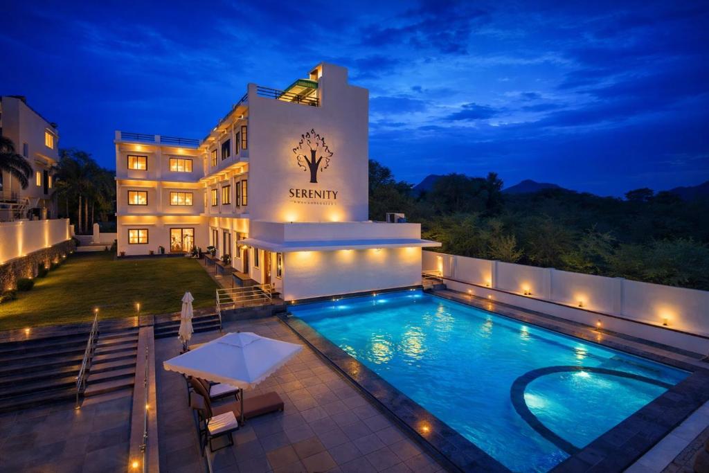 a hotel with a swimming pool at night at Serenity Hill Resort Near 2Km Fateh Sagar Lake Udaipur in Udaipur