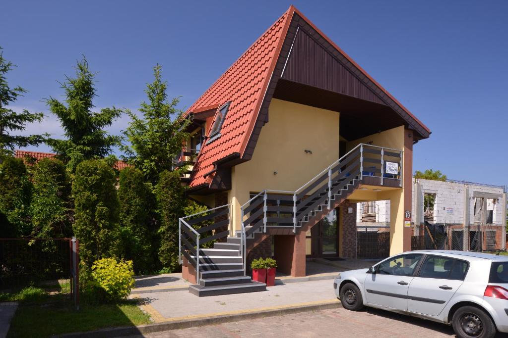 a house with a staircase and a car parked in front at Pokoiki Krotka10 in Ustronie Morskie