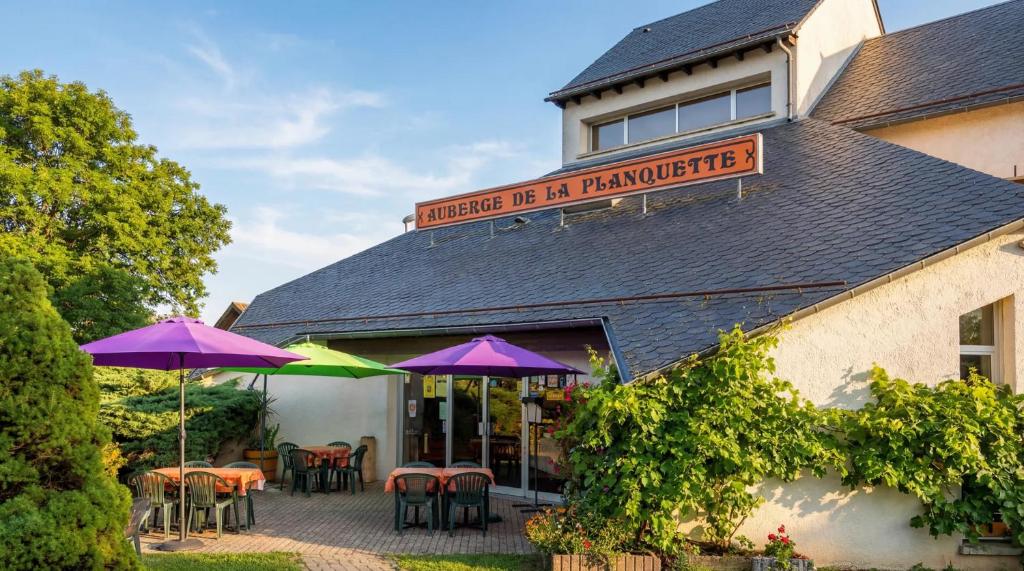 a restaurant with tables and umbrellas in front of a building at Hotel La Planquette in Réquista