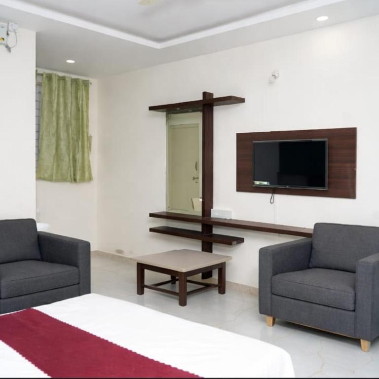 a living room with two chairs and a flat screen tv at Sai Grands Stay In in Bangalore