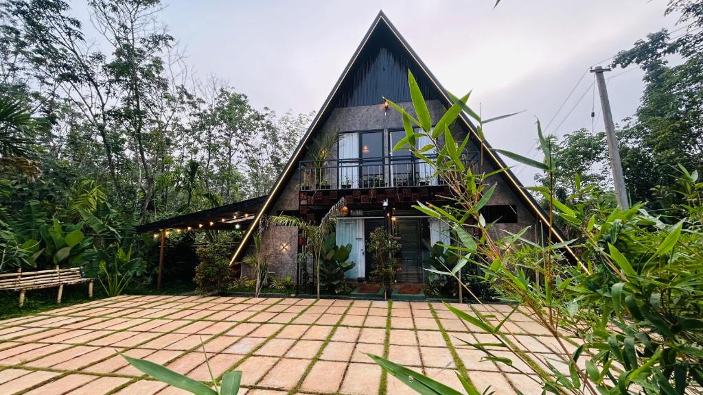 a house with a gambrel roof with a patio at The Western Inn in Mananthavady