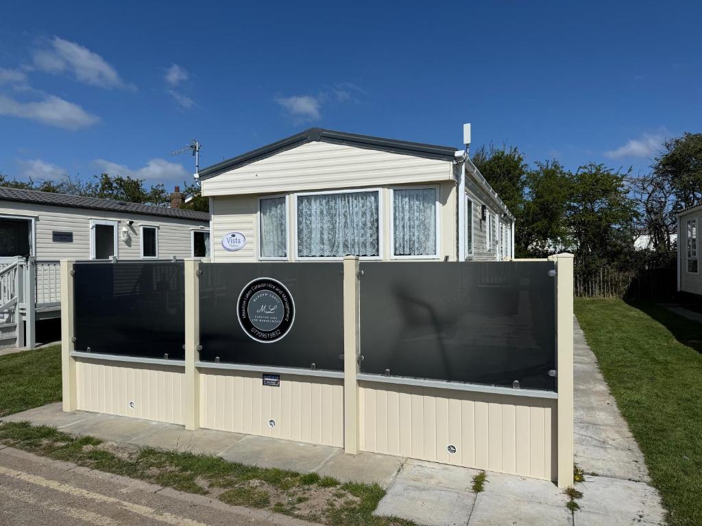 a fence with a large screen in front of a house at Sunnymede i15 Hot Tub - pet friendly, bed linen - Meadow Lakes Caravan & Lodge Hire in Ingoldmells