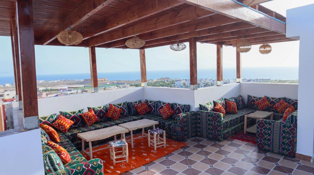 a patio with chairs and a table and the ocean at The Palm Surfhouse in Tamraght Ouzdar