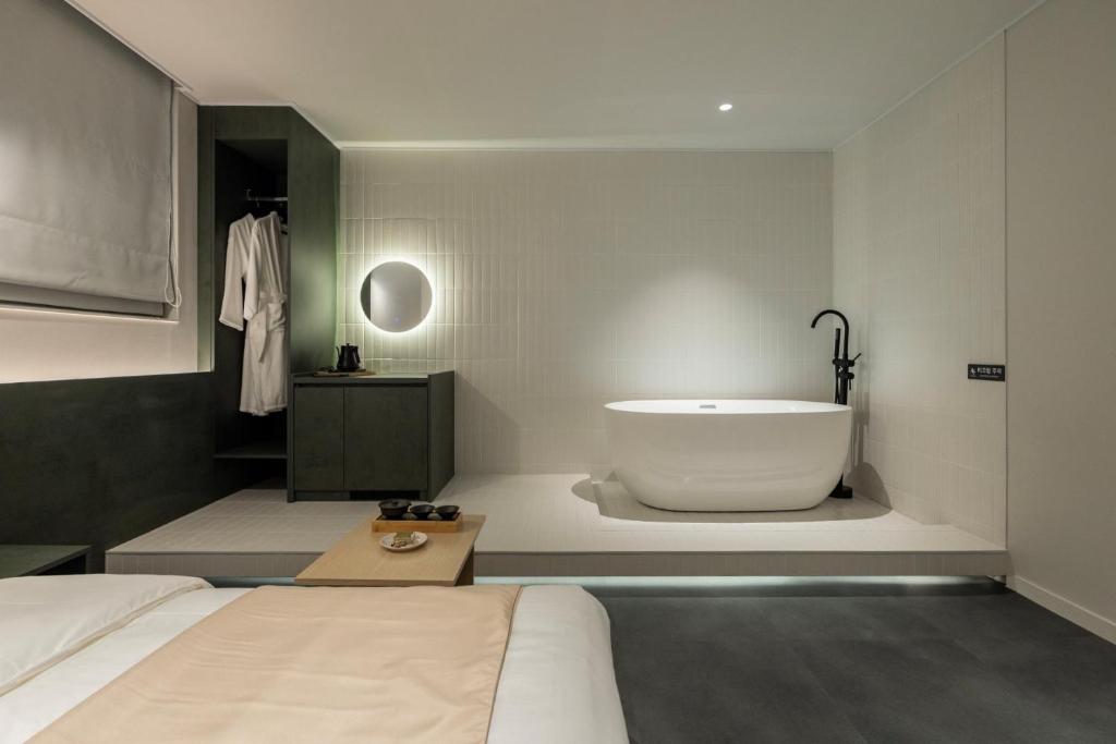 a bedroom with a bathtub and a bed and a bed and a room with at Anook Hotel Suwon Ingye 2 in Suwon
