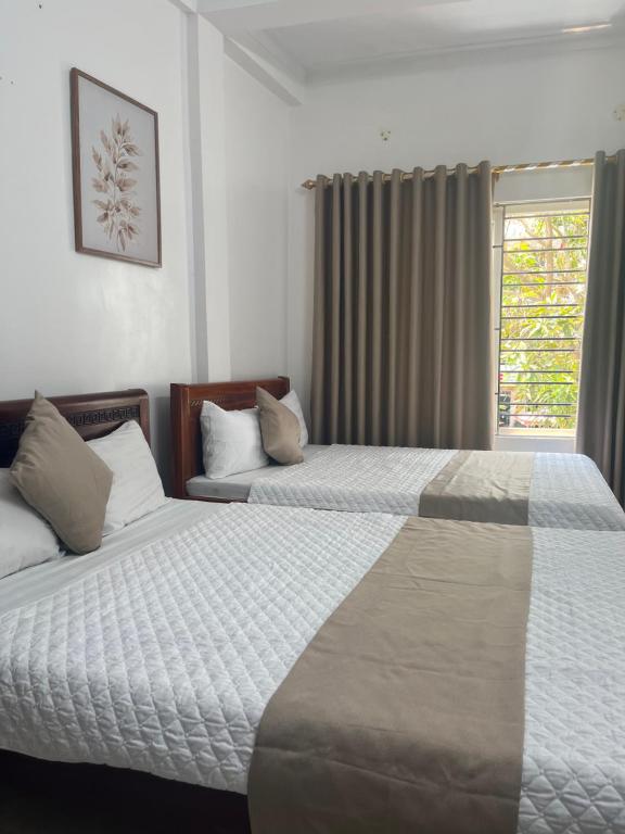 a hotel room with two beds and a window at An Phú Stay & Coffee in Cửa Lô
