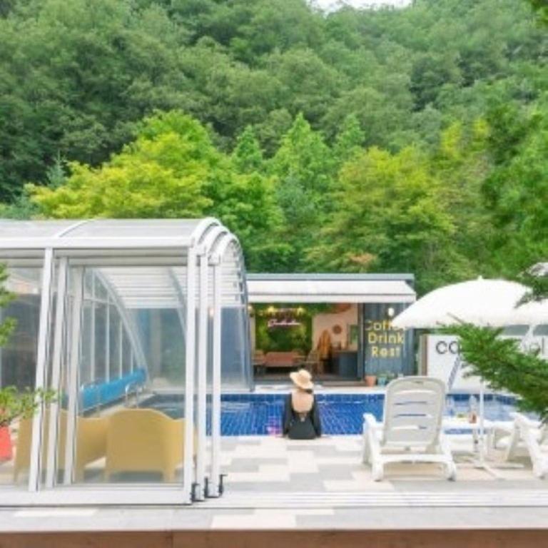 a group of chairs and an umbrella on a patio at Green Soochaehwa Pension Yangyang in Yangyang