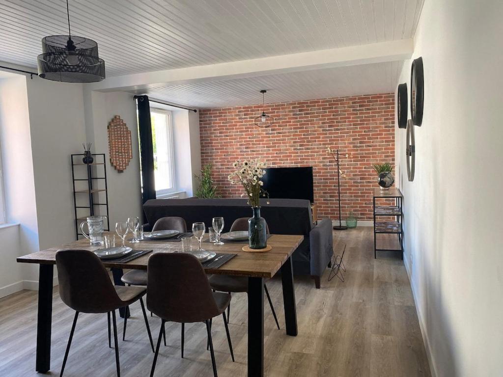 a dining room with a table and chairs and a brick wall at La Factory Saint Aignan in Saint-Aignan