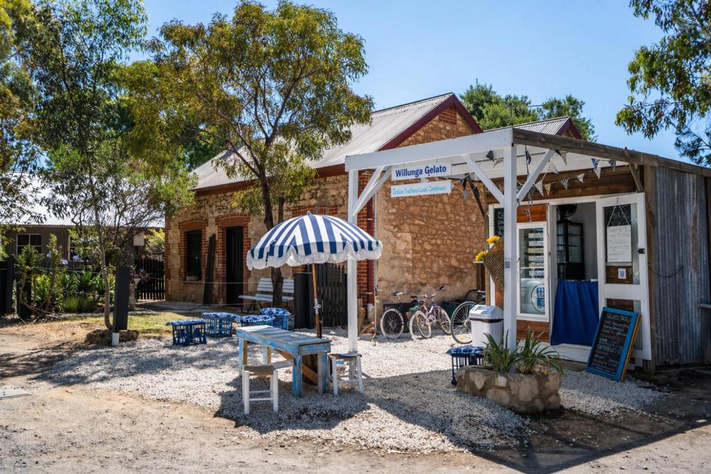 a building with a table and an umbrella at Blacksmith Cottage - Stay in Blacksmith's Lively Hub in Aldinga