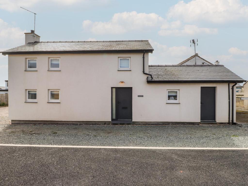 a white house with a garage at Kiloran in Rhosneigr