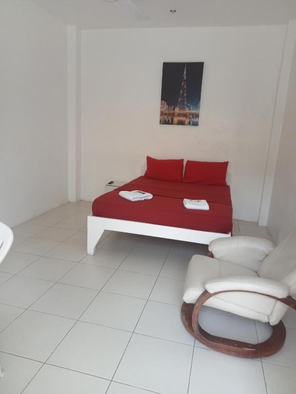 a bedroom with a red bed and a chair at J and M Pension House in Dipolog