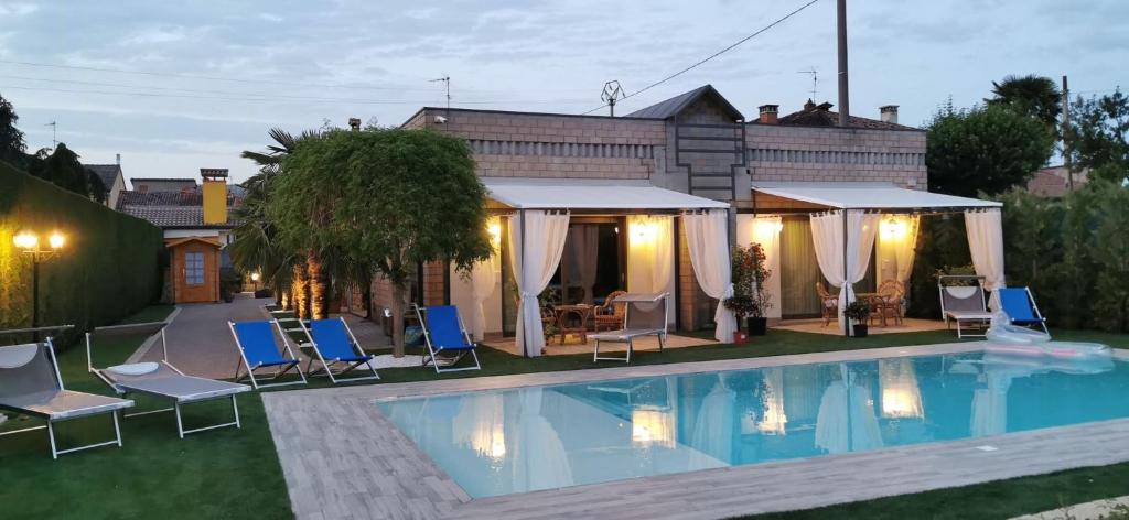 a swimming pool with chairs and a gazebo at Manor Villa Among Veneto's Orchards in Castelbaldo