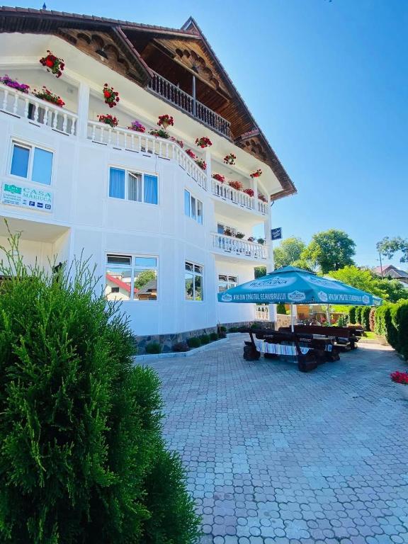 a large white building with umbrellas in front of it at Pensiunea Casa Mariuca in Văleni