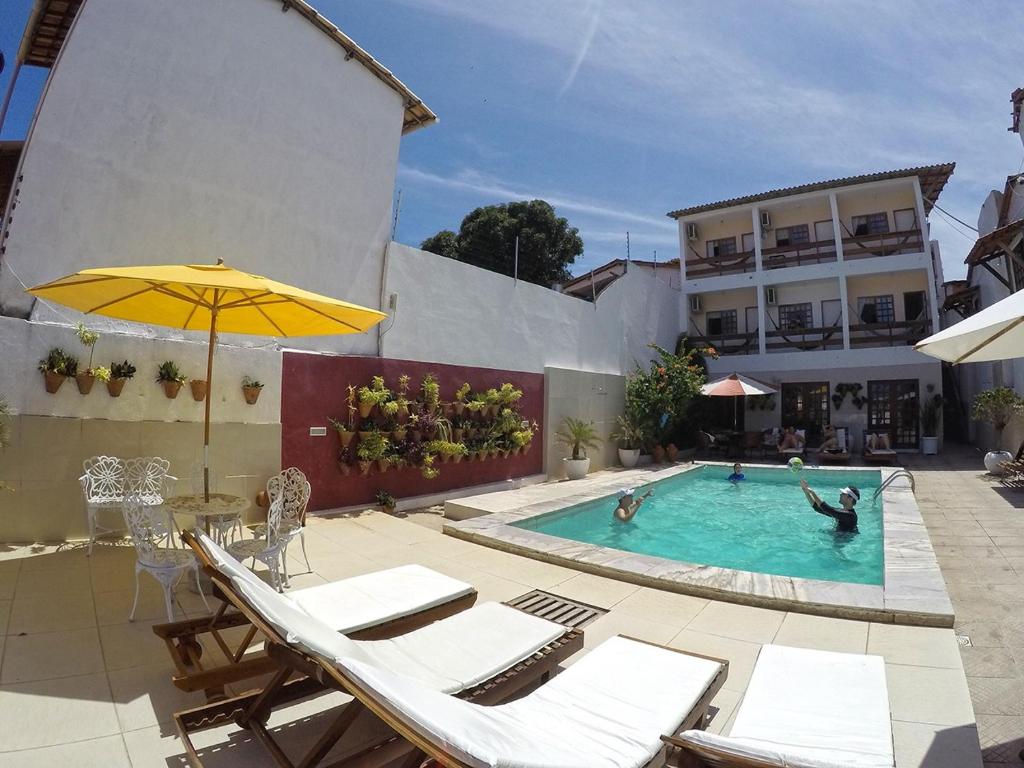 a swimming pool with chairs and an umbrella at Pousada Praiana in Pipa