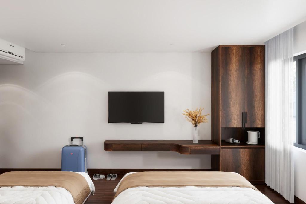 a bedroom with two beds and a tv on the wall at Thùy Dung 68 Hotel in Dong Hoi