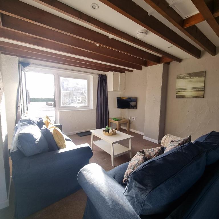 a living room with a blue couch and a table at Fadrun Cottage in Llangian