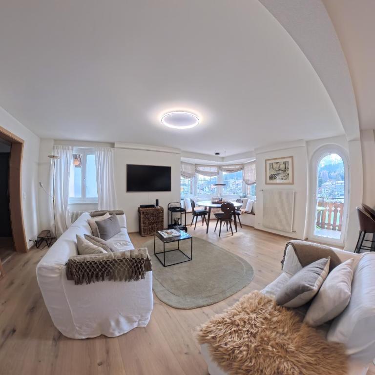 a living room with a white couch and a table at 5 room apartment for 8 people at Bergcafe Aurora Lenzerheide in Lenzerheide
