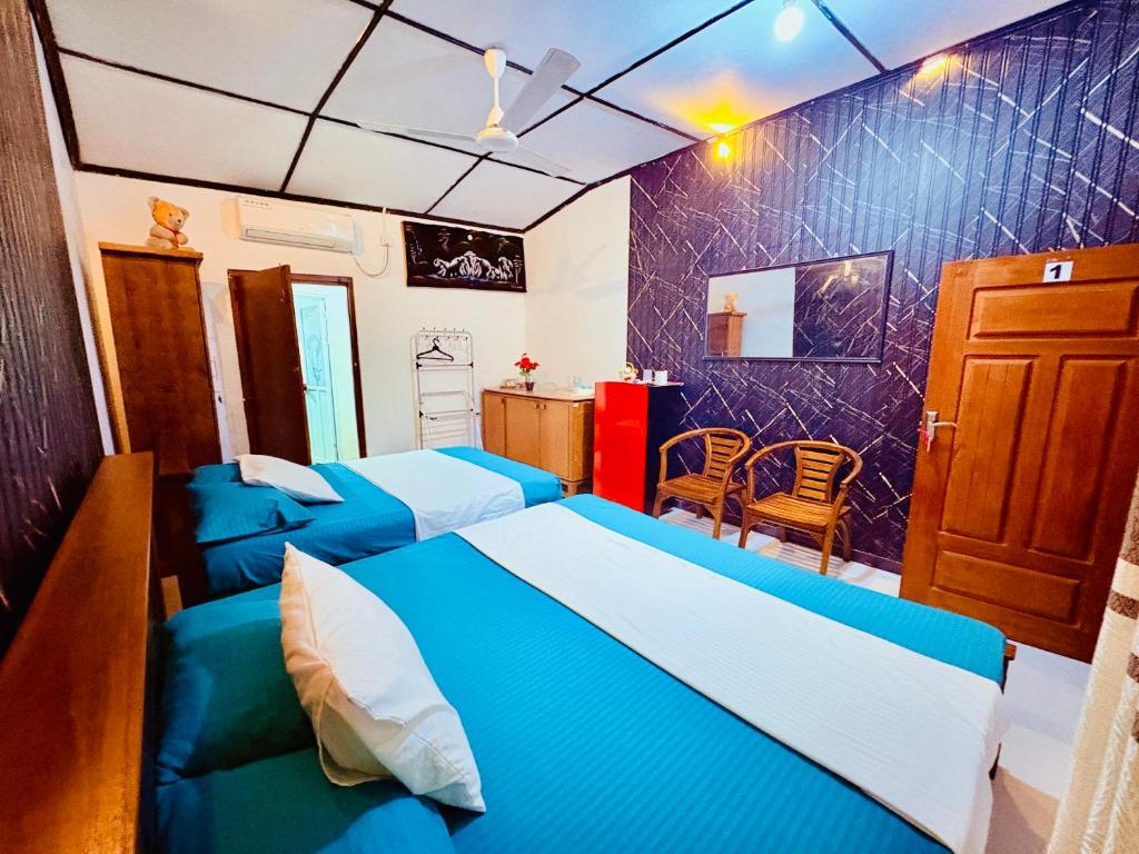 a bedroom with two blue beds and a kitchen at Shehan villa in Beruwala