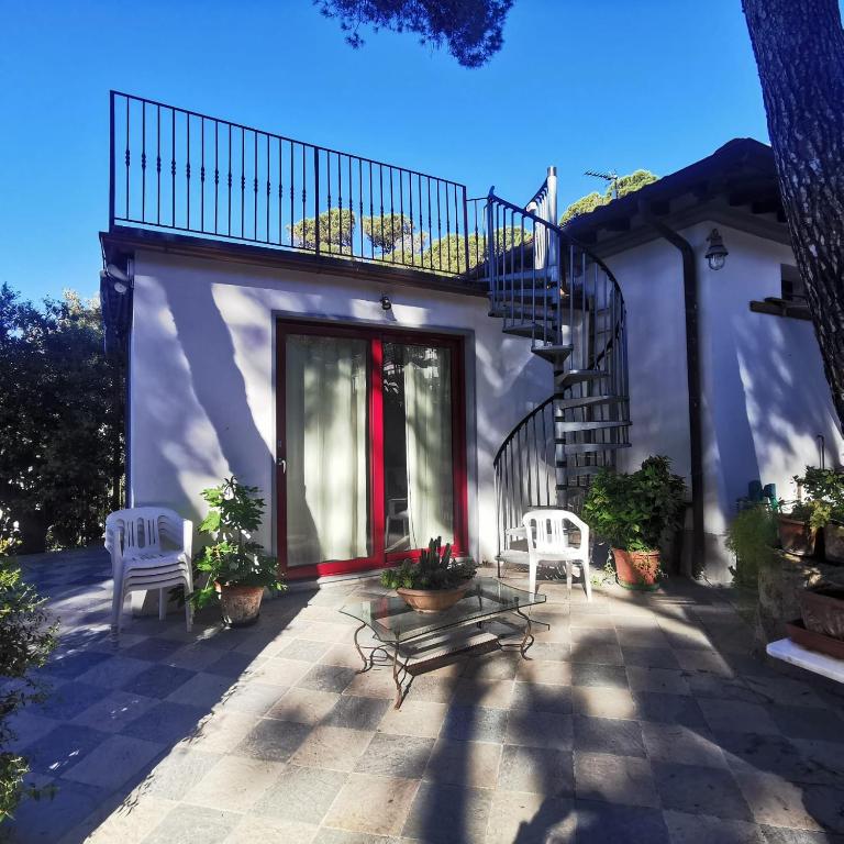 a house with a patio with two chairs and a staircase at Casa Nel Verde Vista Mare in Quercianella