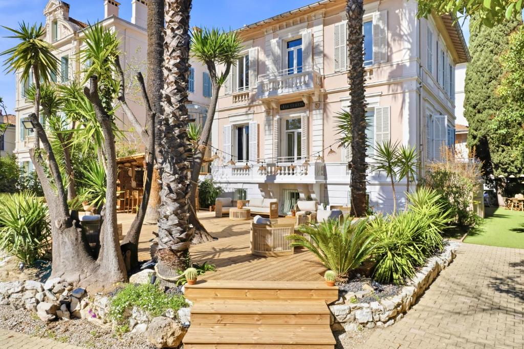 a house with palm trees and a wooden walkway at Villa Claudia Hotel Cannes Centre - Parking in Cannes