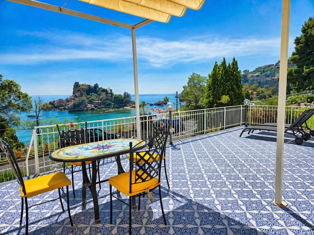 a table and chairs on a balcony with a view of the water at Taormina Isola Bella Apartment - Taormina Holidays in Taormina