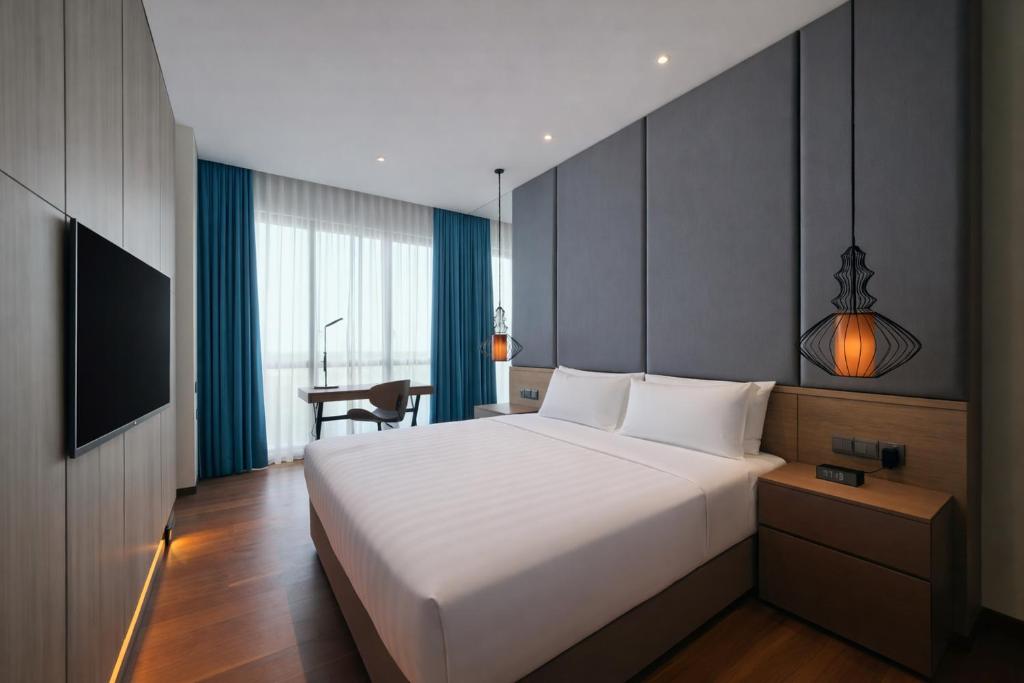 a bedroom with a large white bed and a desk at Dao By Dorsett Puteri Cove in Johor Bahru