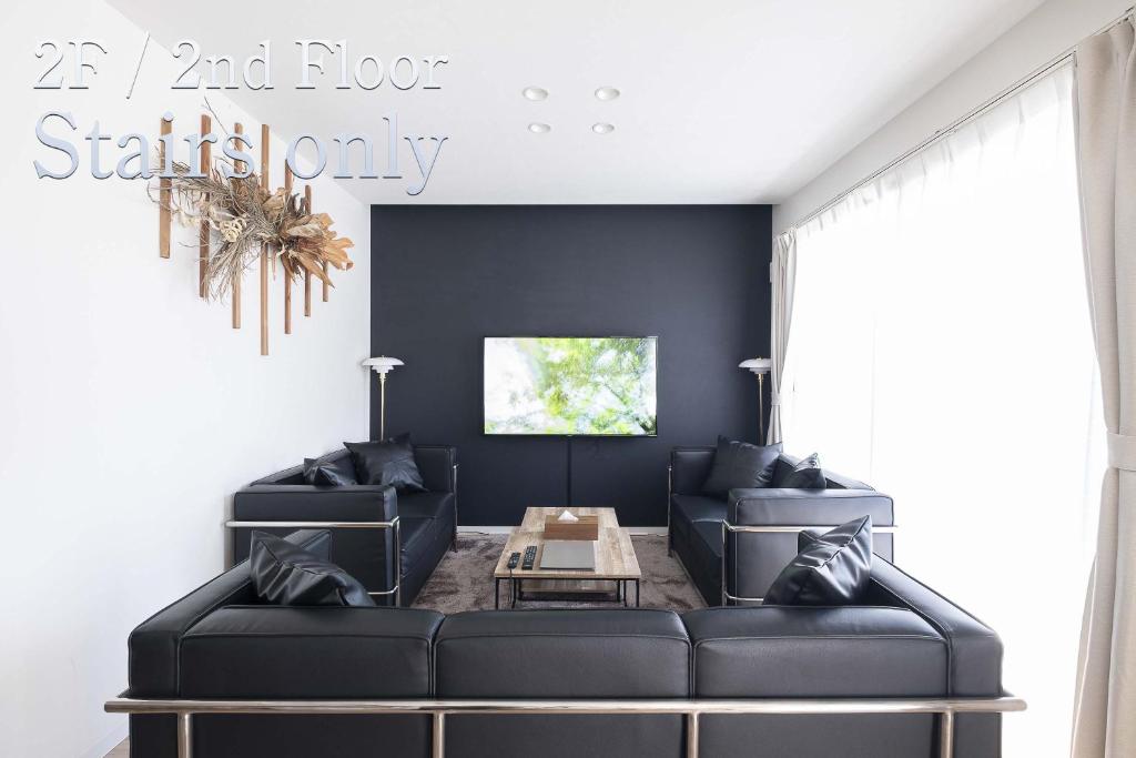 a living room with two black couches and a table at Kitasaito Terrace C in Asahikawa