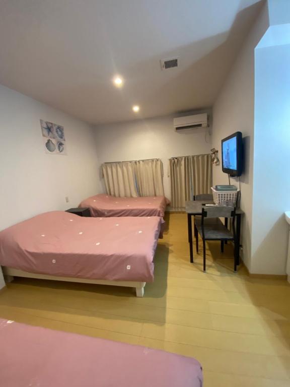 two beds in a room with a desk and a television at Hotel MR TOMO ATAMI 102 in Atami