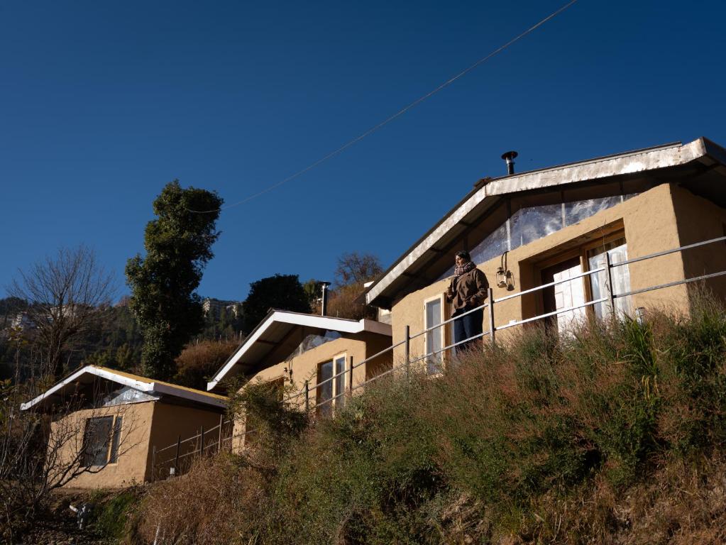 a man standing on the balcony of a house at Nomad Eco Retreat in Shimla