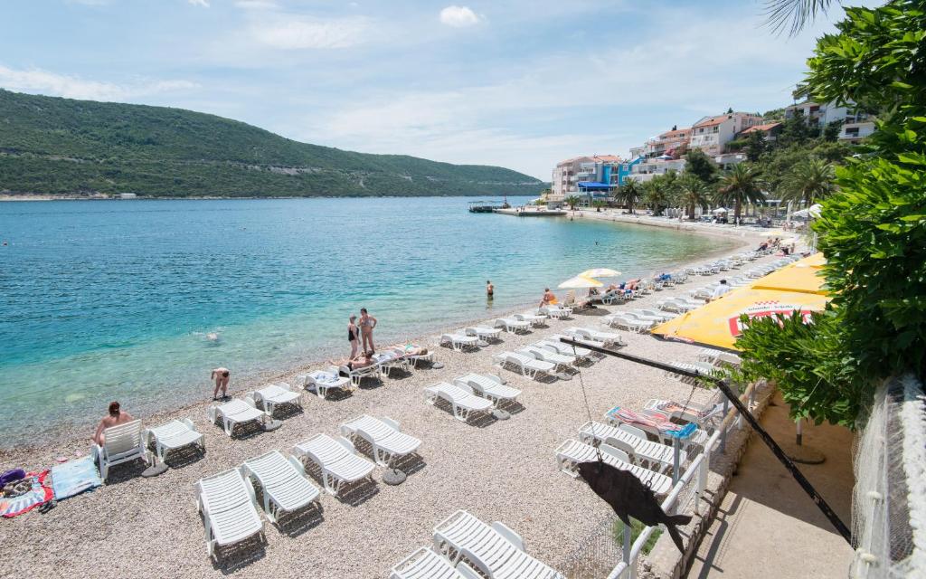 a beach with chairs and people in the water at Hotel AGAVA in Neum