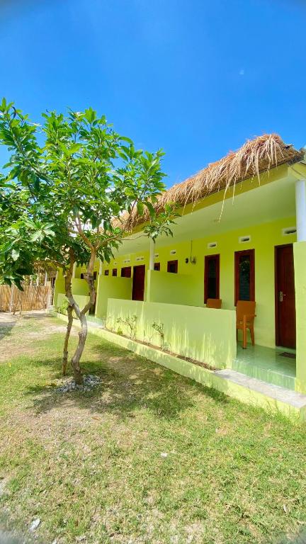 a yellow house with a tree in front of it at Mango Lodge in Gili Gede