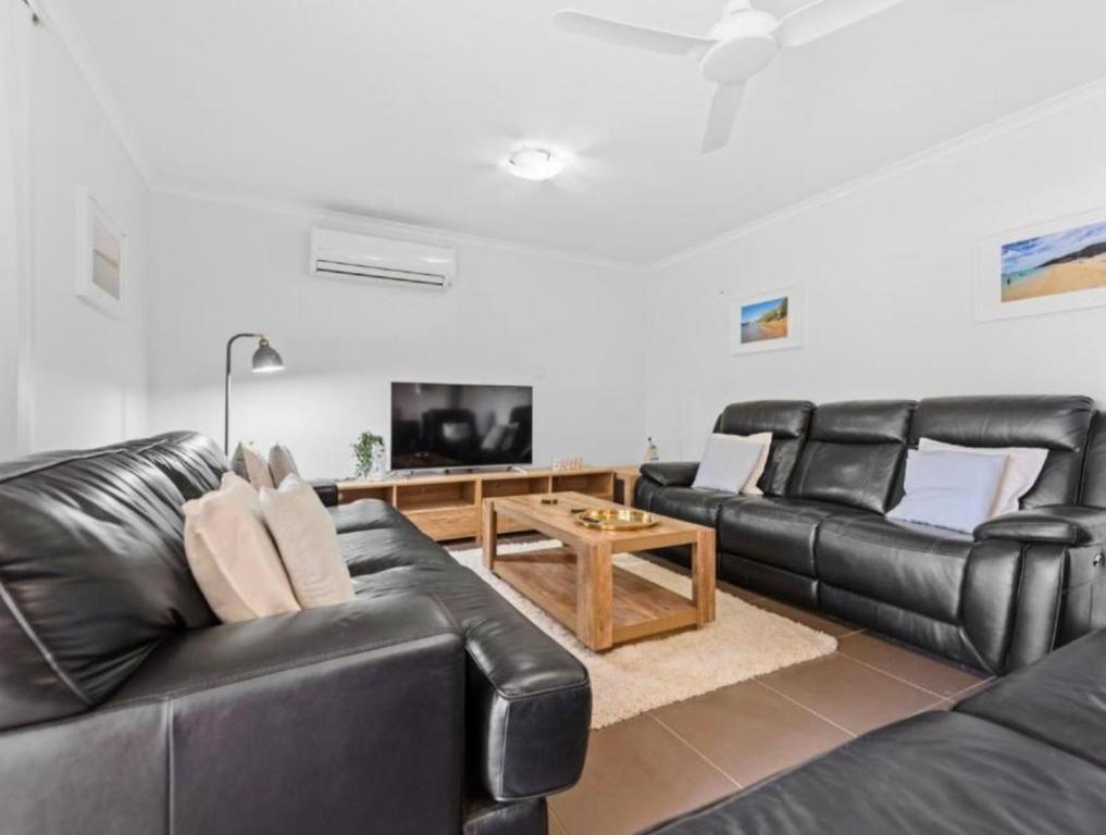 a living room with black leather furniture and a flat screen tv at Riverstone Crescent Residence in Caloundra West