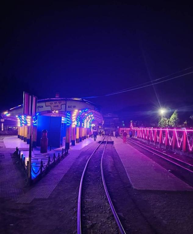 a train station at night with lights on the tracks at Cloud Hill Homestay in Jālāpahār