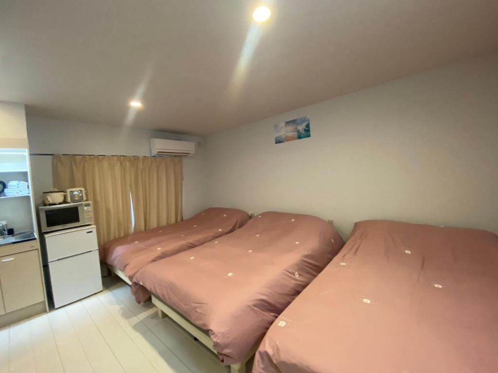 two beds in a small room with a kitchen at Hotel MR TOMO ATAMI 301 in Atami