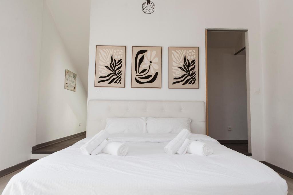 a bedroom with a white bed with four pictures on the wall at Square'71 - T4 Duplex avec terrasse - espace détente in Chalon-sur-Saône