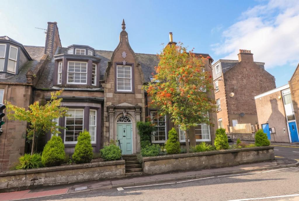 an old brick house with a blue door on a street at Rowan Tree House in Brechin