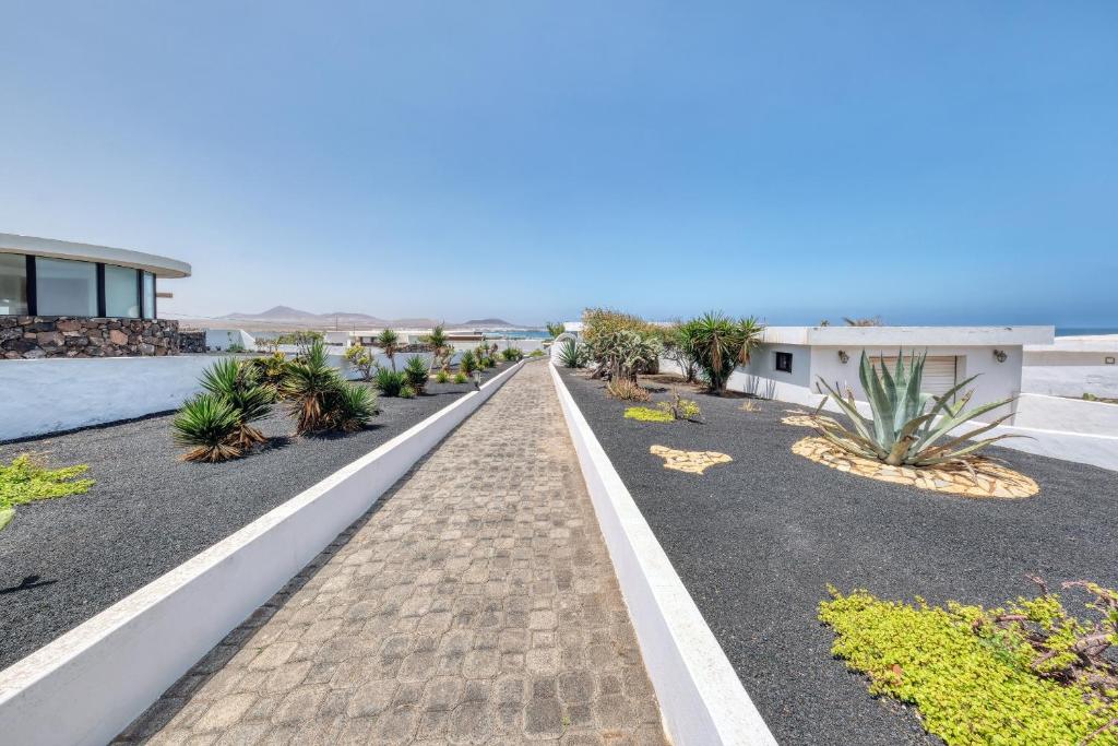 a road leading to a house with plants at Bungalow Olas del Risco - Ocean views - Beach 2 min By Lanzarote Vacation Homes in Famara