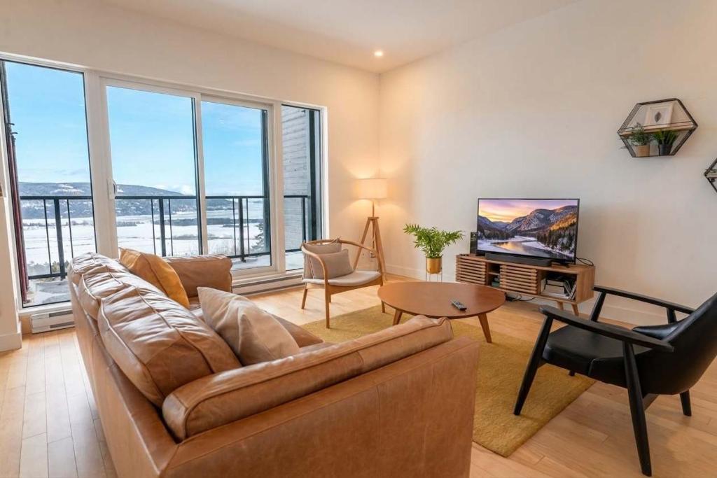 a living room with a couch and a table at 309 - Luxury Condo - Spectacular View & Pool in Baie-Saint-Paul