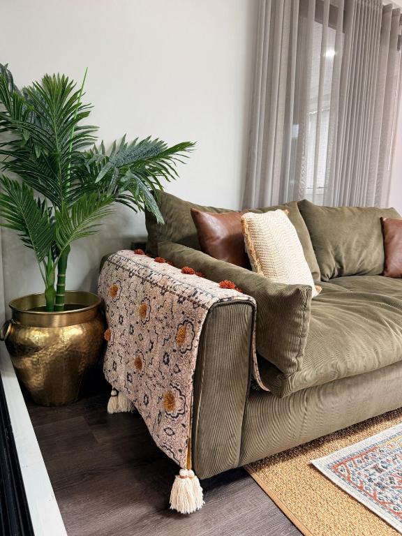 a couch in a living room with a potted plant at Pacific Palms Retreat - Entire Home in Plumpton Sleeps 9 - 8-Car Parking Near Eastern Creek in Rooty Hill