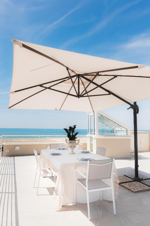 a white table and chairs under a large white umbrella at Casa OliVera in Viareggio