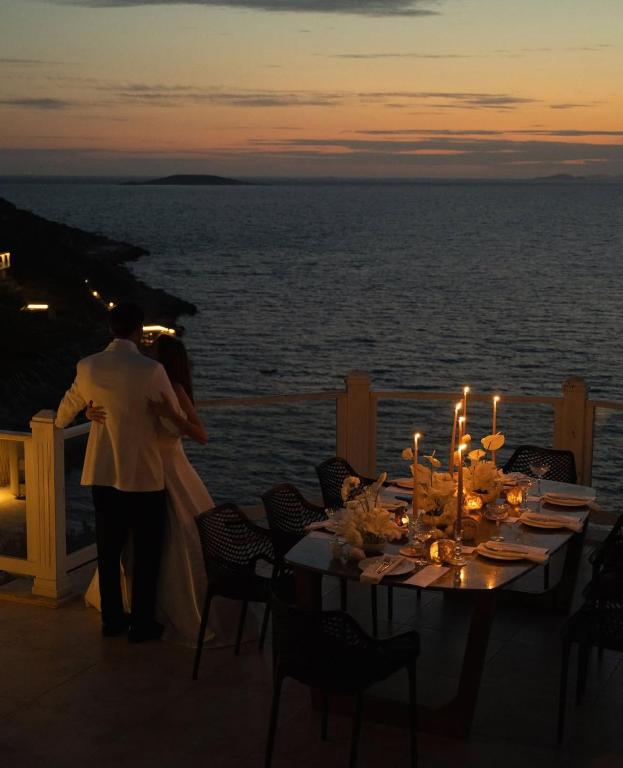 a man and woman standing on a balcony with a table with candles at Villa Alis stunning sea view with Infinity Pool in Kaş