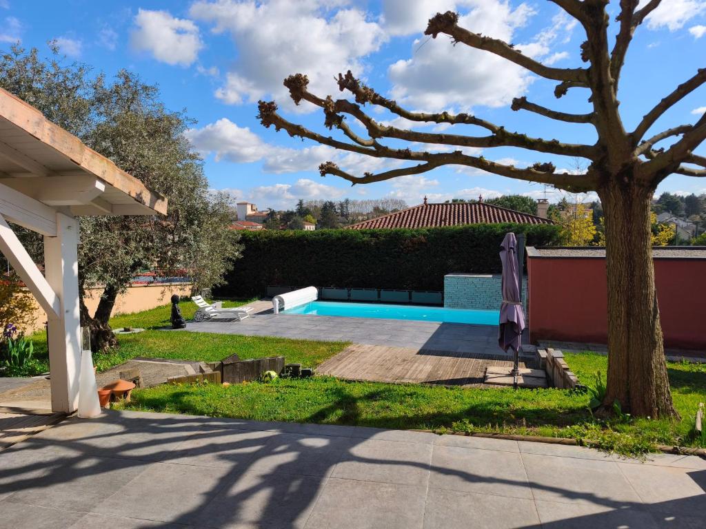 a swimming pool in a yard with a tree at Maison Montellier - piscine in Charly
