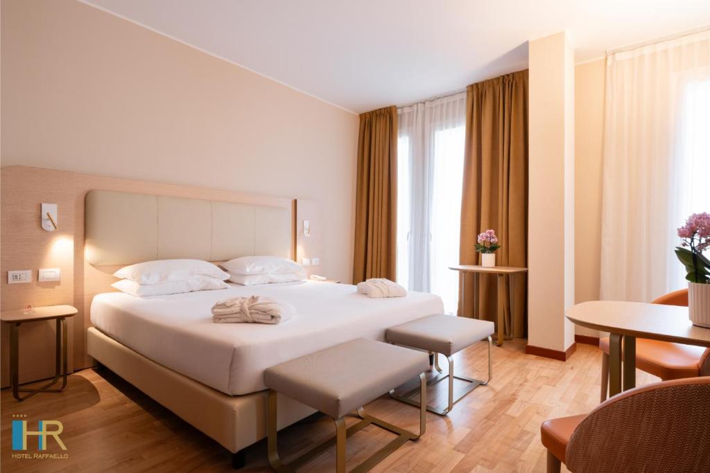 a bedroom with a large white bed and a table at Hotel Raffaello in Milan